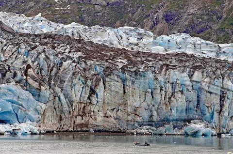 Small boat with two people in front of the huge front of a glacier Glacier Bay Stock Photos