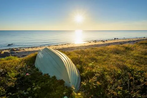 Small boat upside down on beach at sunset in summer at Sealand Odde in Odsherred Stock Photos