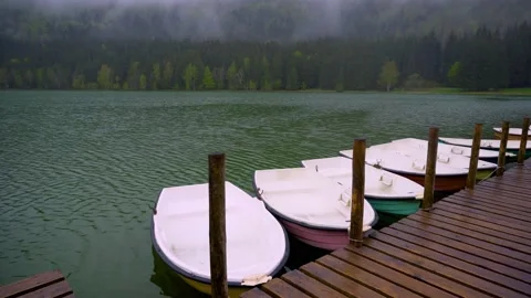 Small boats floating on the mountain forest lake close to the wooden pier. Video stock 150593734