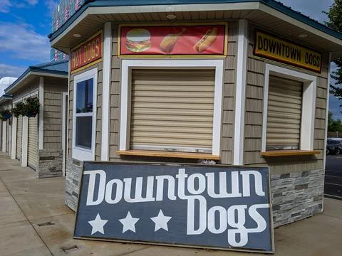 A small booth or store thats closed with a sign out front reading Downtown Dogs Foto stock
