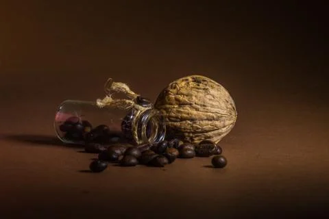 A small bottle with coffee beans and walnut on a brown background Stock Photos