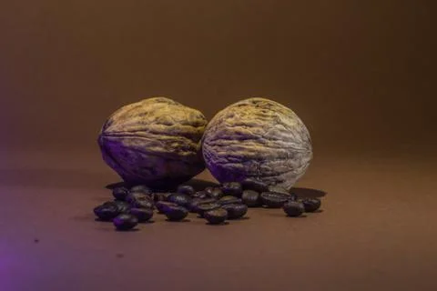 A small bottle with coffee beans and walnuts on a brown background Stock Photos