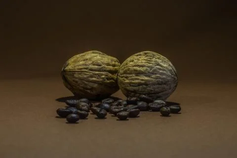 A small bottle with coffee beans and walnuts on a brown background Stock Photos