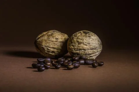A small bottle with coffee beans and walnuts on a brown background Stock Photos