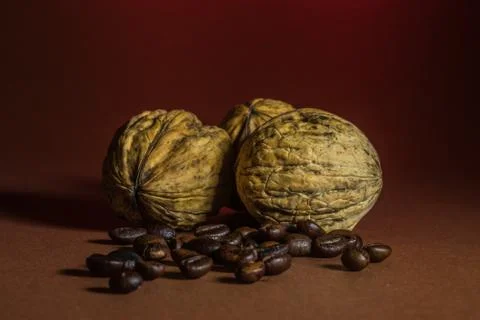 A small bottle with coffee beans and walnuts on a brown background Stock Photos