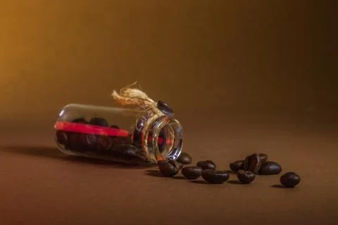 A small bottle with coffee beans on a brown background Stock Photos