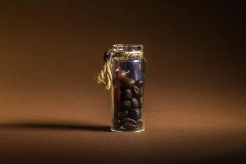 A small bottle with coffee beans on a brown background Stock Photos
