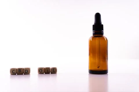 A small bottle with a dropper full of CBD oil or any other oil on white backg Foto stock