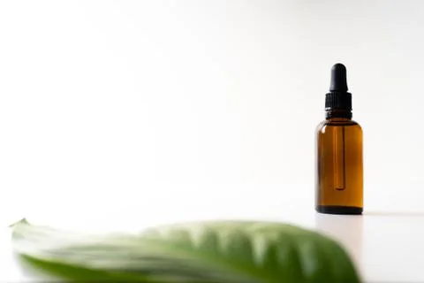A small bottle with a dropper full of CBD oil or any other oil and a green le Stock Photos