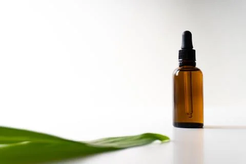 A small bottle with a dropper full of CBD oil or any other oil and a green le Stock Photos