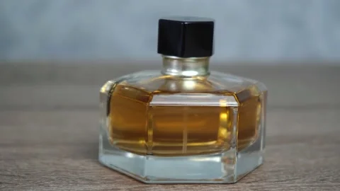 Small bottle of orange perfume sitting on a wooden table Stockbeeldmateriaal 139113122
