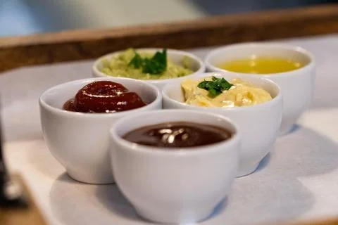 Small bowls with different sauces on a tray in a restaurant Stock Photos