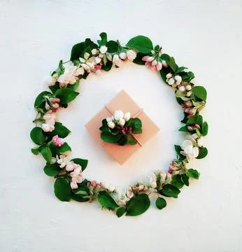 A small box with a gift in a circle of white-pink inflorescences Stock Photos