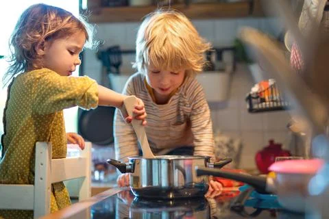 Small boy and girl indoors in kitchen at home, helping with cooking. Stock Photos