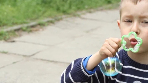 Small boy blowing bubbles. Happy child blowing soap bubbles in spring park. Stock Footage 107251035