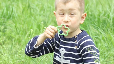Small boy blowing bubbles. Happy child blowing soap bubbles in spring park. Stock Footage 107251186