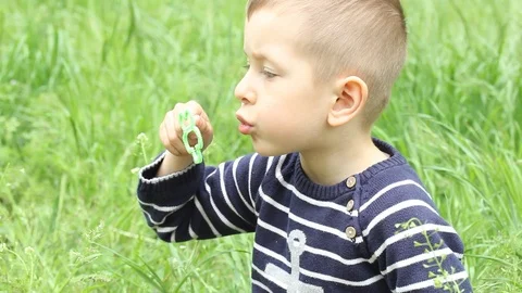 Small boy blowing bubbles. Happy child blowing soap bubbles in spring park. Stock Footage 107251205