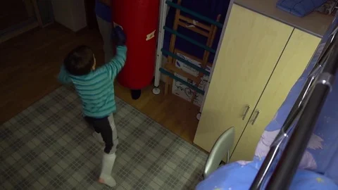 Small boy in boxing gloves trains kicks on boxing bag Stock-Footage 82585460