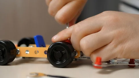 A small boy builds a car model from a metal construction kit, twisting the parts Video stock 127845365