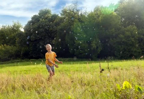 Small boy catching soap bubbles Stock Photos
