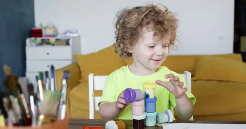 Small boy with cheerful expression builds colourful tower Stockbeeldmateriaal 285325037