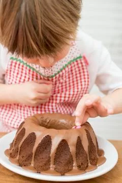 Small boy decorating ring cake with coloured chocolate beans Stock Photos
