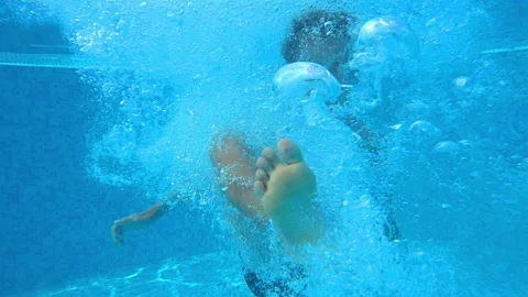 Small boy diving in the pool and looking at the camera, large bubbles formin Stock Footage 150211391