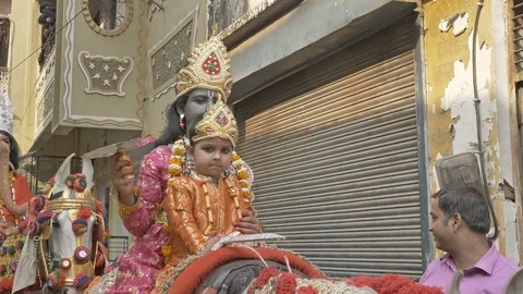A small boy dressed as Lord Krishna with a small girl sitting on a horse Stock Footage 111300029