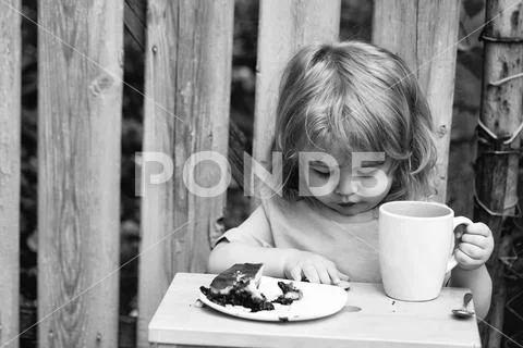Small boy eating pie near wooden fence Stock Photos