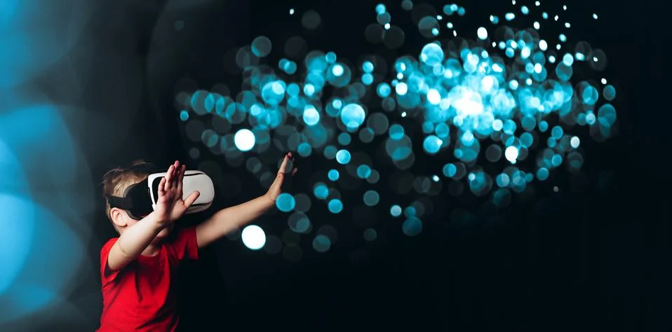 Small Boy experiencing virtual reality on black background with light luminou Stock-Fotos