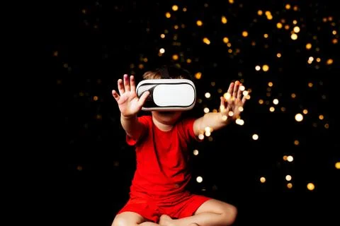 Small Boy experiencing virtual reality on black background with light luminou Stock-Fotos
