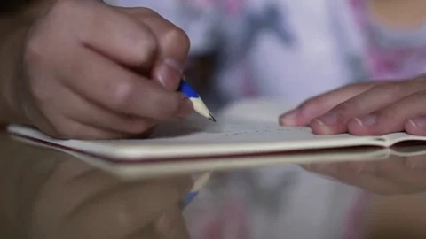Small boy hand holding pen and writing homework at table with reflection Stockbeeldmateriaal 80666629