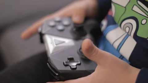 Small boy hands holding wireless gamepad and playing video games in a livingroom Stock Footage 102416123