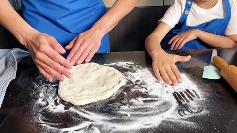 Small boy helping mother prepare dough for baking bread in home kitchen. Stock Footage 285315437