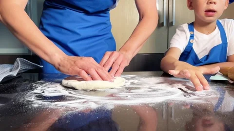 Small boy helping mother prepare dough for baking bread in home kitchen. Stock Footage 285315504