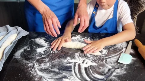 Small boy helping mother prepare dough for baking bread in home kitchen. Home Stock Footage 295188216