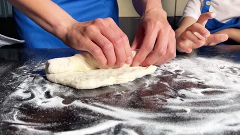 Small boy helping mother prepare dough for baking bread in home kitchen. Home Stock Footage 295188220