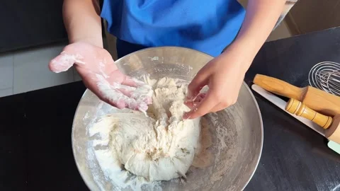 Small boy helping mother prepare dough for baking bread in home kitchen. Home Stock Footage 295190858