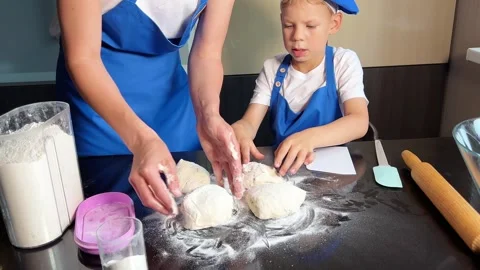 Small boy helping mother prepare dough for baking bread in home kitchen. Home Stock Footage 295190919