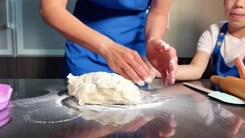 Small boy helping mother prepare dough for baking bread in home kitchen. Home Stock Footage 295190946