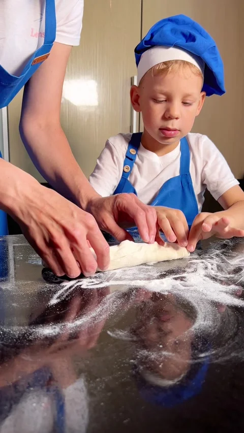 Small boy helping mother prepare dough for baking bread in home kitchen. Home Stock Footage 295192339