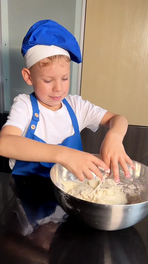 Small boy helping mother prepare dough for baking bread in home kitchen. Home Stock Footage 295192628