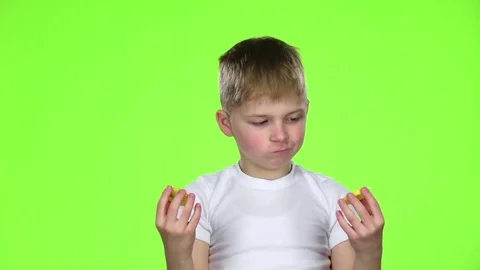 Small boy holds a slice of a lemon licks and curls from acid. Green screen. Slow Stock Footage 75793968