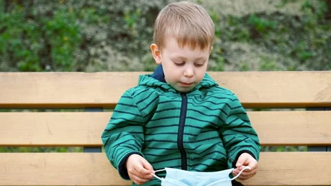 Small boy kid trying to put on medical mask to protect from coronavirus Stock Footage 133641595
