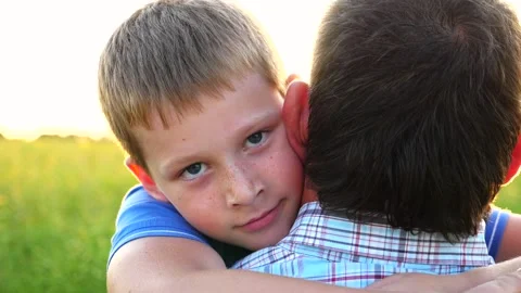 Small boy looking into camera and hugging his dad against bright sunlight Stock Footage 327908548