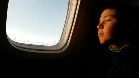 Small boy looking out of an airplane window and dreaming about something Stock Footage