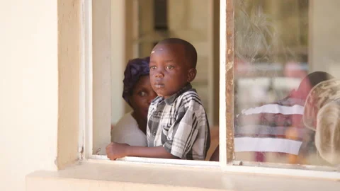 Small boy looking out window in the waiting room of district hospital in Stock Footage 335030173