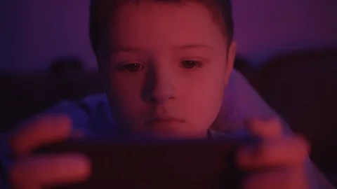 A small boy looks at a smartphone before going to bed in a dark room play games Stock Footage 127168571