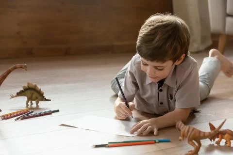 Small boy lying on floor drawing in album Stock Photos