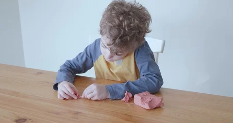 Small boy making snail out of modelling clay Video stock 128218991